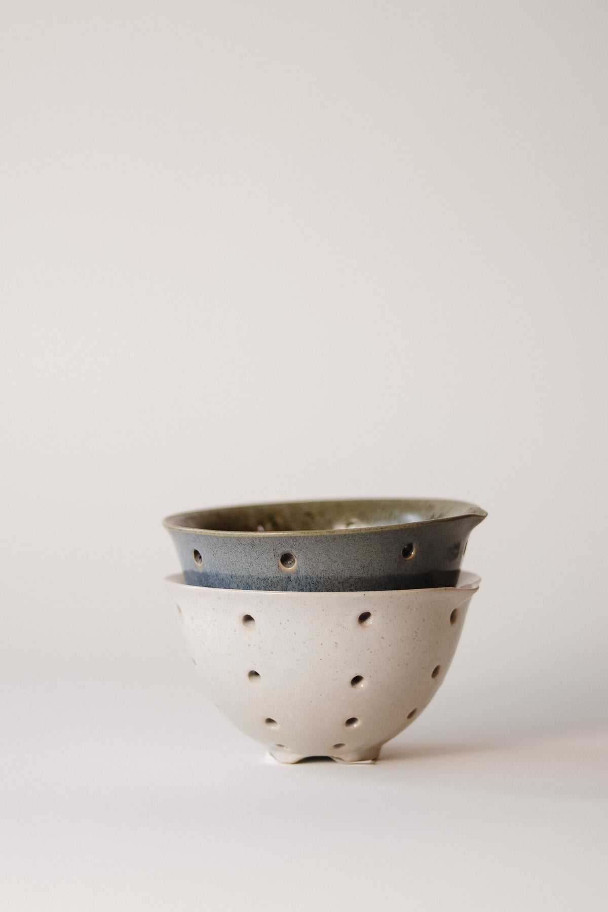 A rustic stoneware bowl designed for collecting and washing a variety of berries.